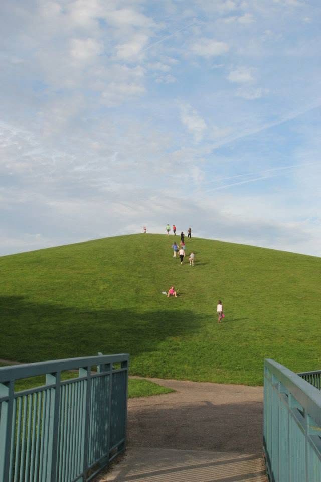 The grassed mound in 2013, closely mown, with families walking and playing on it